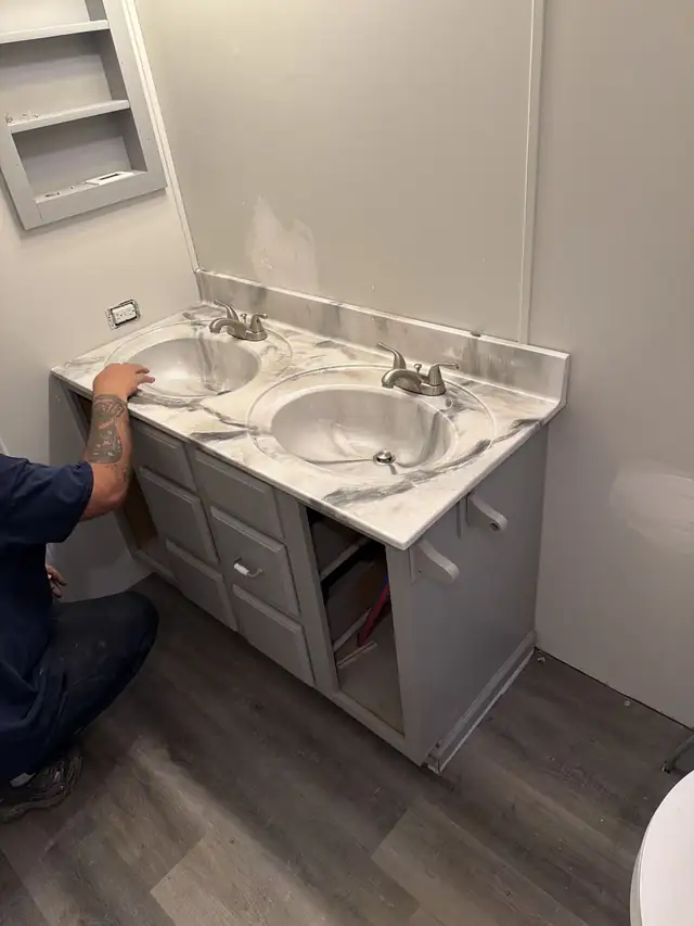 Installer finishing a double-sink bathroom vanity top in white and gray epoxy