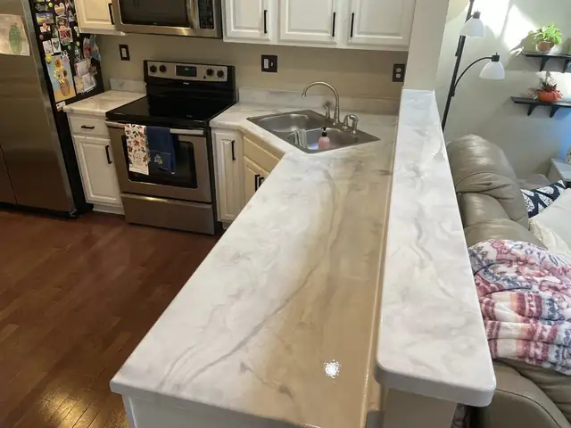Kitchen with honey oak cabinets and resurfaced cream and white epoxy countertops with a raised bar ledge