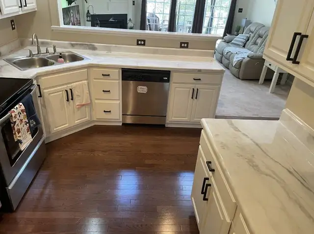 White kitchen counters with gray veining, white cabinets and a dark wood floor