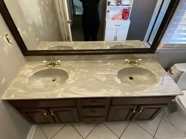 Double-sink bathroom vanity with a resurfaced cream marble-look epoxy top and dark wood cabinet