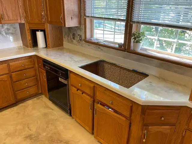 Kitchen counters resurfaced in cream and white epoxy with wood cabinets under a row of windows