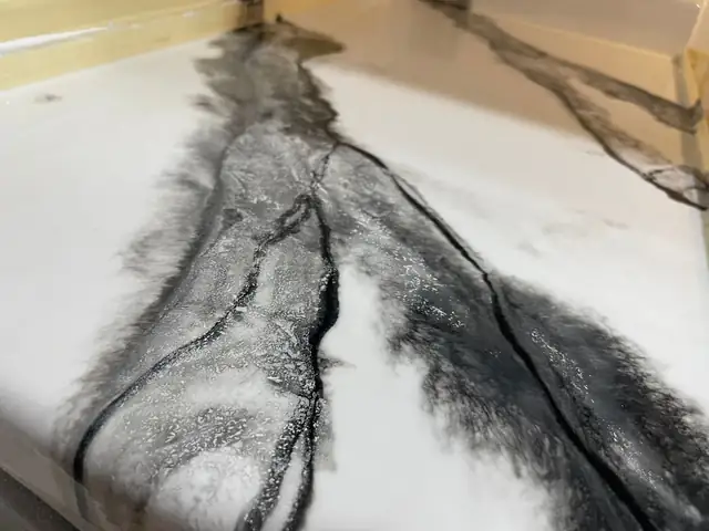 Close-up of a glossy white epoxy countertop with dramatic black and gray veining