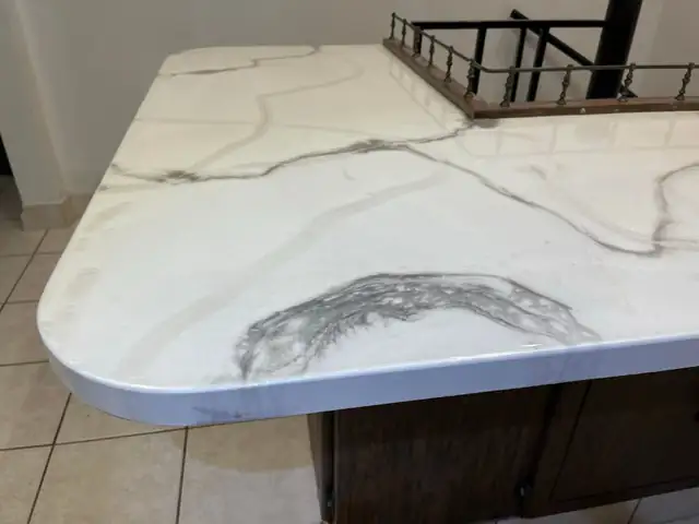 White epoxy countertop with black veining and a rounded corner above a tile floor